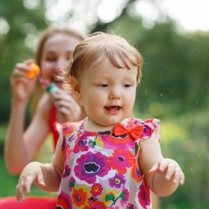 Mum with daughter blowing soap bubbles in park Mum with small daughter blowing soap bubbles in park